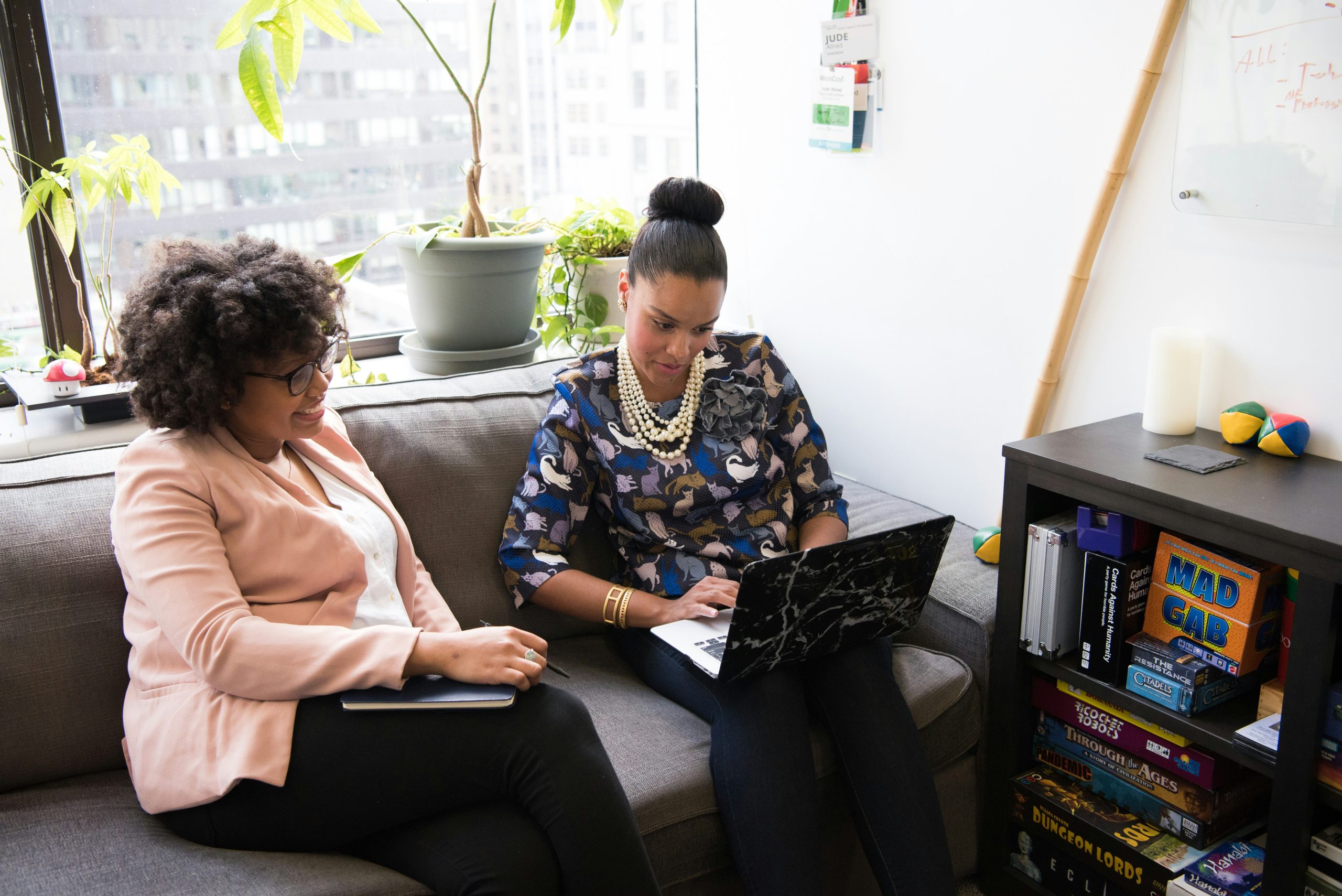 Two women collaborate over a laptop.
